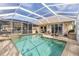 Screened pool area with spa, outdoor kitchen, and patio seating at Heron Creek Golf & Country Club at 5599 Hidden Oak Ct, North Port, FL 34287