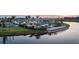 Stunning aerial view of a community pool, lake, pier, tennis court, and luxury homes at sunset at 18056 Cherished Loop, Bradenton, FL 34211