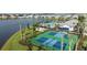Aerial view showcasing community pickleball courts, pool, and a tranquil lakeside setting at 18064 Cherished Loop, Bradenton, FL 34211