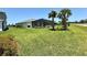 Expansive backyard featuring a screened-in pool area, lush green lawn, and palm trees at 43819 Cattleman Dr, Punta Gorda, FL 33982