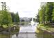 Scenic pond view with fountain, framed by lush greenery and a glimpse of the building at 5613 Legacy Crescent Pl # 201, Riverview, FL 33578