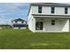 Exterior of a white house with a covered patio and a spacious green lawn at 13610 Wolfpack Rd, Hudson, FL 34667