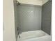 Clean and functional bathtub with a gray tiled shower, highlighting bathroom comfort at 13610 Wolfpack Rd, Hudson, FL 34667