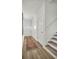 Bright and airy hallway featuring wood floors, white walls, a decorative rug, and staircase at 14004 Emerald Fields Dr, Hudson, FL 34667