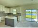 Bright kitchen featuring white cabinetry, an island, granite countertops, and sliding glass doors at 14004 Emerald Fields Dr, Hudson, FL 34667
