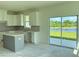 Bright kitchen featuring white cabinetry, an island, granite countertops, and sliding glass doors at 14004 Emerald Fields Dr, Hudson, FL 34667