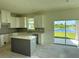 Bright kitchen featuring white cabinetry, an island, granite countertops, and sliding glass doors at 14004 Emerald Fields Dr, Hudson, FL 34667