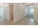 Bright hallway featuring neutral tile flooring, laundry room, and doorways leading to other rooms at 16866 Fiesta Dr, Port Charlotte, FL 33953