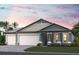 Charming single-Gathering home with a three-car garage and well-manicured lawn under a pink and purple sunset at 1688 Lugano Cir, Nokomis, FL 34275