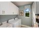 Practical laundry room with washer, dryer, cabinets, and natural light at 1688 Lugano Cir, Nokomis, FL 34275