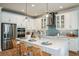 Bright kitchen featuring white cabinets, stainless steel appliances, a center island with seating, and decorative pendant lighting at 200 Vistera Blvd, North Venice, FL 34275