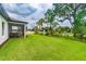 Expansive green backyard with a view of the home's screened-in lanai and the surrounding community at 2046 Sunset Preserve Way, Port Charlotte, FL 33953