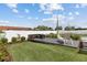 This backyard boasts a deck with stylish outdoor furniture, a lush lawn, landscaping, and an in-ground pool at 567 Whippoorwill Dr, Venice, FL 34293