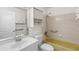 A quaint bathroom has a white sink, toilet, medicine cabinet, and a yellow bathtub with tile surround at 567 Whippoorwill Dr, Venice, FL 34293