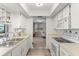 A view of the kitchen showing white appliances and cabinets and view to living area at 567 Whippoorwill Dr, Venice, FL 34293