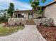 Welcoming front entrance with stone accents, a brick path, and lush, colorful landscaping at 233 Snyder Dr, Venice, FL 34292
