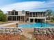 Gorgeous outdoor pool with stone-covered home in the background, perfect for relaxation and entertainment at 233 Snyder Dr, Venice, FL 34292