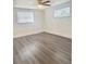 Bright, empty bedroom featuring modern gray wood flooring and a ceiling fan and two windows at 4934 Avery Rd, New Port Richey, FL 34652