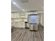 Spacious kitchen featuring stainless steel refrigerator, white cabinets, and light gray wood-look floors at 4934 Avery Rd, New Port Richey, FL 34652