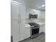 Modern kitchen featuring stainless steel appliances, ample white cabinetry, and sleek light gray floors at 4934 Avery Rd, New Port Richey, FL 34652