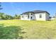 A view of the back of the house including the lanai and backyard with vibrant green lawn at 13527 Ainsworth Ln, Port Charlotte, FL 33981