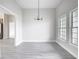 Minimalist dining area filled with natural light, gray luxury vinyl plank floors, and modern chandelier at 14112 Monserrate Ln, Port Charlotte, FL 33981