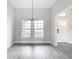 Bright dining area featuring a modern chandelier and two large windows, illuminating the gray wood floors at 14112 Monserrate Ln, Port Charlotte, FL 33981