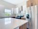 Well-lit kitchen with island, stainless steel appliances, and wood grain and white cabinets at 14112 Monserrate Ln, Port Charlotte, FL 33981