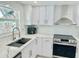 Modern kitchen with white cabinets, stainless steel appliances, and a farmhouse sink at 4229 Floramar Ter, New Port Richey, FL 34652