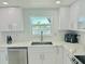 Modern kitchen with white cabinets, stainless steel appliances, and a window overlooking the water at 4229 Floramar Ter, New Port Richey, FL 34652