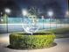 View of a tennis court featuring lush green bushes and multiple light posts for night play at 2070 World Parkway Blvd # 50, Clearwater, FL 33763
