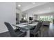 Modern dining room with a glass table, gray chairs, and an open view to the living room at 2228 Valrico Forest Dr, Valrico, FL 33594