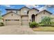 Two-story house with tan exterior, three-car garage, and landscaping at 1005 Sonesta Ave, Brandon, FL 33511