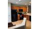 Kitchen featuring tan tile flooring, wooden cabinetry, black appliances and a white door at 10453 Westpark Preserve Blvd, Tampa, FL 33625