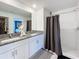 Bathroom with dual sinks, granite counters, white cabinets, and a tiled shower at 12764 Weston Oaks Ln, Riverview, FL 33579