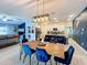 Open-concept dining area featuring a wood table with blue velvet chairs and modern light fixture, adjacent to the kitchen at 12764 Weston Oaks Ln, Riverview, FL 33579