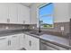Close-up of kitchen sink with modern faucet, gray countertops, stainless steel dishwasher and white cabinets at 8489 Topeka Cir, Port Charlotte, FL 33981