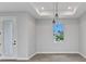 Bright living room featuring a tile floor, modern light fixture, recessed ceiling, and a glass panel door at 8489 Topeka Cir, Port Charlotte, FL 33981
