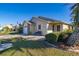 Tan single-story house with a landscaped lawn, a brick garage, and a bench at 5846 Greenbriar Ct, Zephyrhills, FL 33542