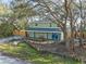 Charming home surrounded by mature trees, featuring bright blue doors and a welcoming front porch at 10020 Jungle St, New Port Richey, FL 34654
