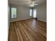 Living room with wood-look flooring, ceiling fan, multiple windows, and a door to the exterior at 7920 Carriage Pointe Dr, Gibsonton, FL 33534