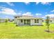 Rear exterior view of the home, showcasing a sliding glass door, green grass, and young trees at 9093 Players Dr, Weeki Wachee, FL 34613