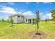 Exterior rear view of the home showcasing the spacious yard with newly planted trees at 9093 Players Dr, Weeki Wachee, FL 34613