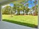 This backyard view from the covered patio features lush green grass and mature shade trees at 9093 Players Dr, Weeki Wachee, FL 34613