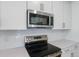 Close-up of a modern kitchen featuring stainless steel appliances and sleek white cabinets at 9093 Players Dr, Weeki Wachee, FL 34613