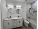 Modern bathroom featuring a double vanity, round mirrors, and a tiled shower-tub combo at 183 Wright Drive, Rotonda West, FL 33947