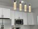 A modern kitchen with a view of cylindrical pendant lights, white cabinets, and stainless steel appliances at 183 Wright Drive, Rotonda West, FL 33947