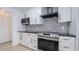 Modern kitchen with black countertops, stainless steel appliances, and patterned backsplash at 4907 Parson Brown Ln, Palm Harbor, FL 34684
