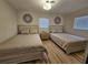 Bright bedroom featuring two twin beds, hardwood floors, and natural light from two windows at 460 Creek Lane Dr, Englewood, FL 34223