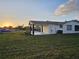 Home exterior showcasing an attached carport and lush green lawn as the sun sets behind it at 460 Creek Lane Dr, Englewood, FL 34223